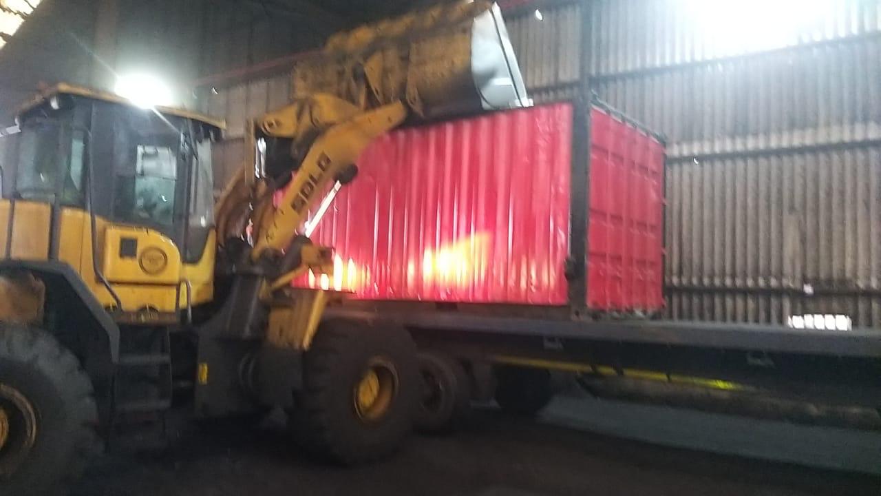 Front end loader handling shipping container in facility warehouse