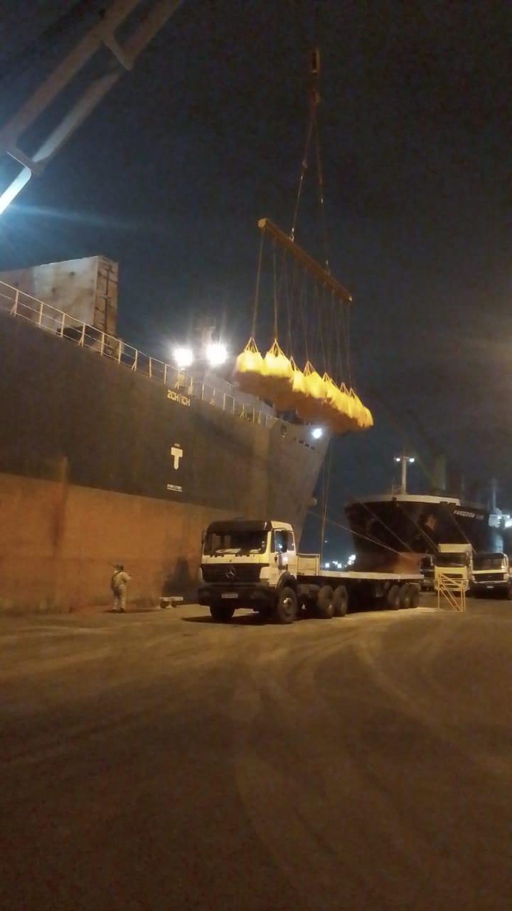 Heavy lift handling equipment transferring bulk bags to cargo truck at night